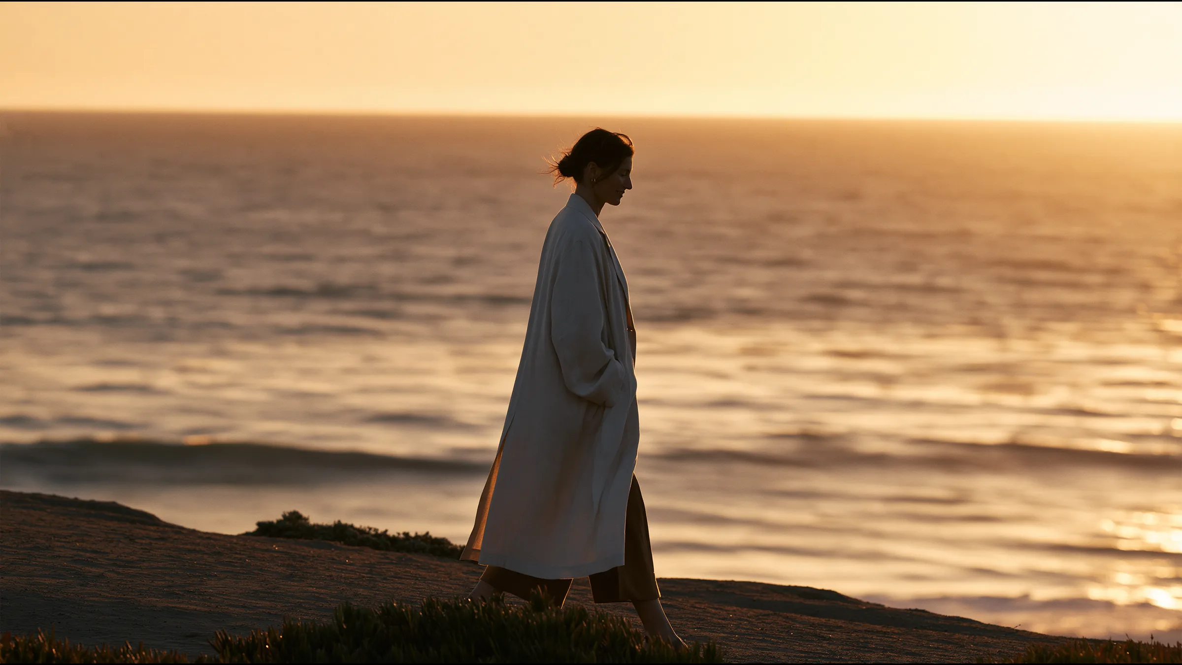 An emergency physician walking out of a minimal clinic onto the Santa Monica bluffs at sunset after her shift, a long exhale and a smile, the Pacific glowing gold