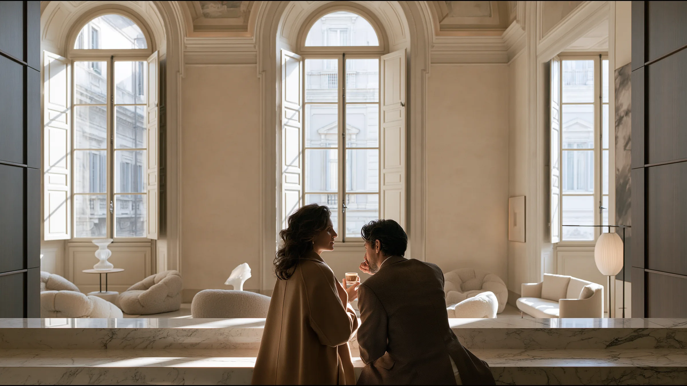 A clinic director sharing an espresso with her operations lead at a marble counter in a frescoed double-height Brera clinic in Milan, quiet relief, tall shutters open to the light