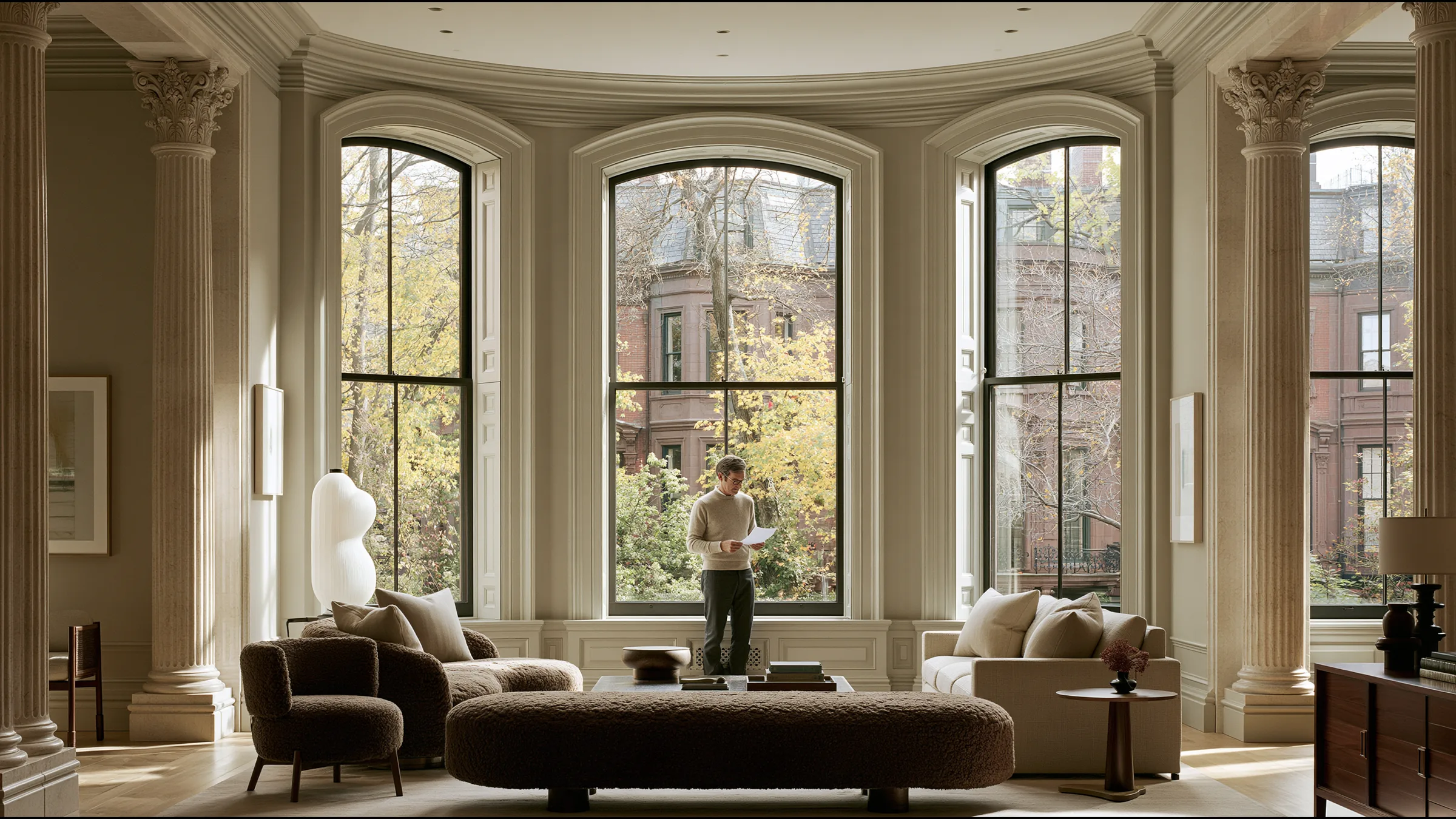 A physician in fine knit standing at a tall window in a grand Back Bay townhouse clinic in Boston, reading a single signed letter with satisfaction, autumn trees and brownstones outside