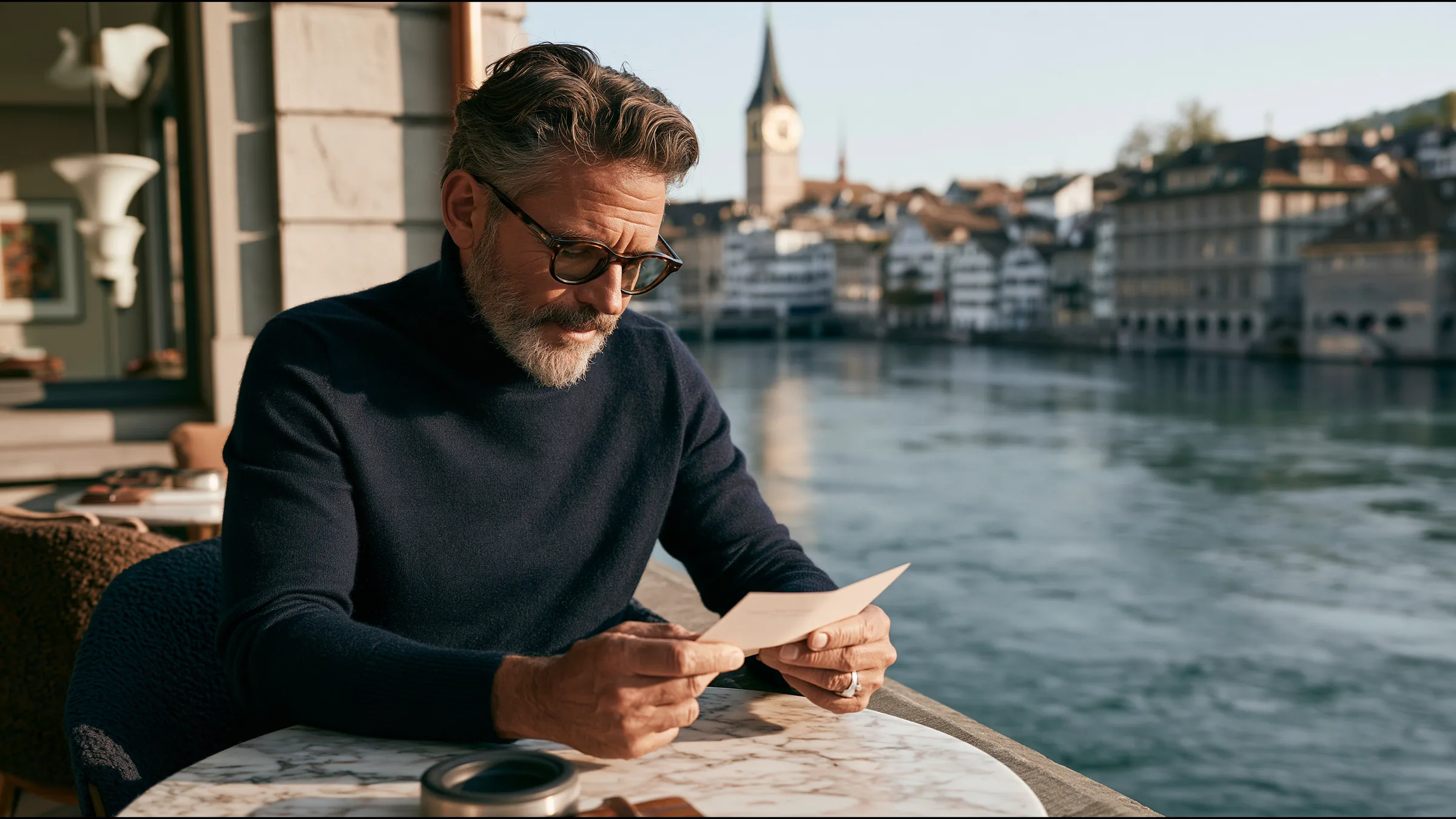A man in his fifties at a marble cafe table by the Limmat in Zurich, reading a single letter with calm satisfaction, the river and old town in soft morning light