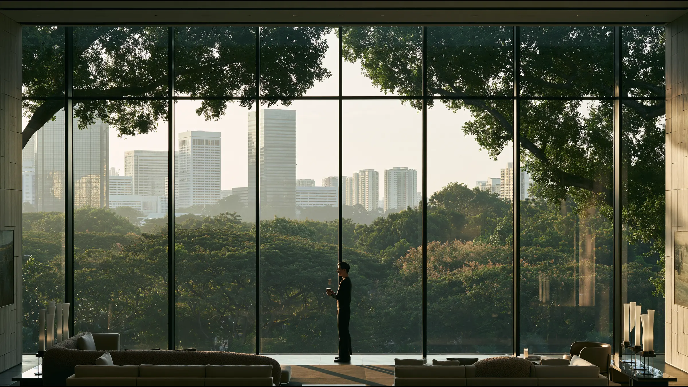A clinician in fine knit standing alone at a vast window over Orchard Road in a calm Singapore specialist centre, coffee in hand, a quiet smile at a smooth morning, towers and trees in soft light