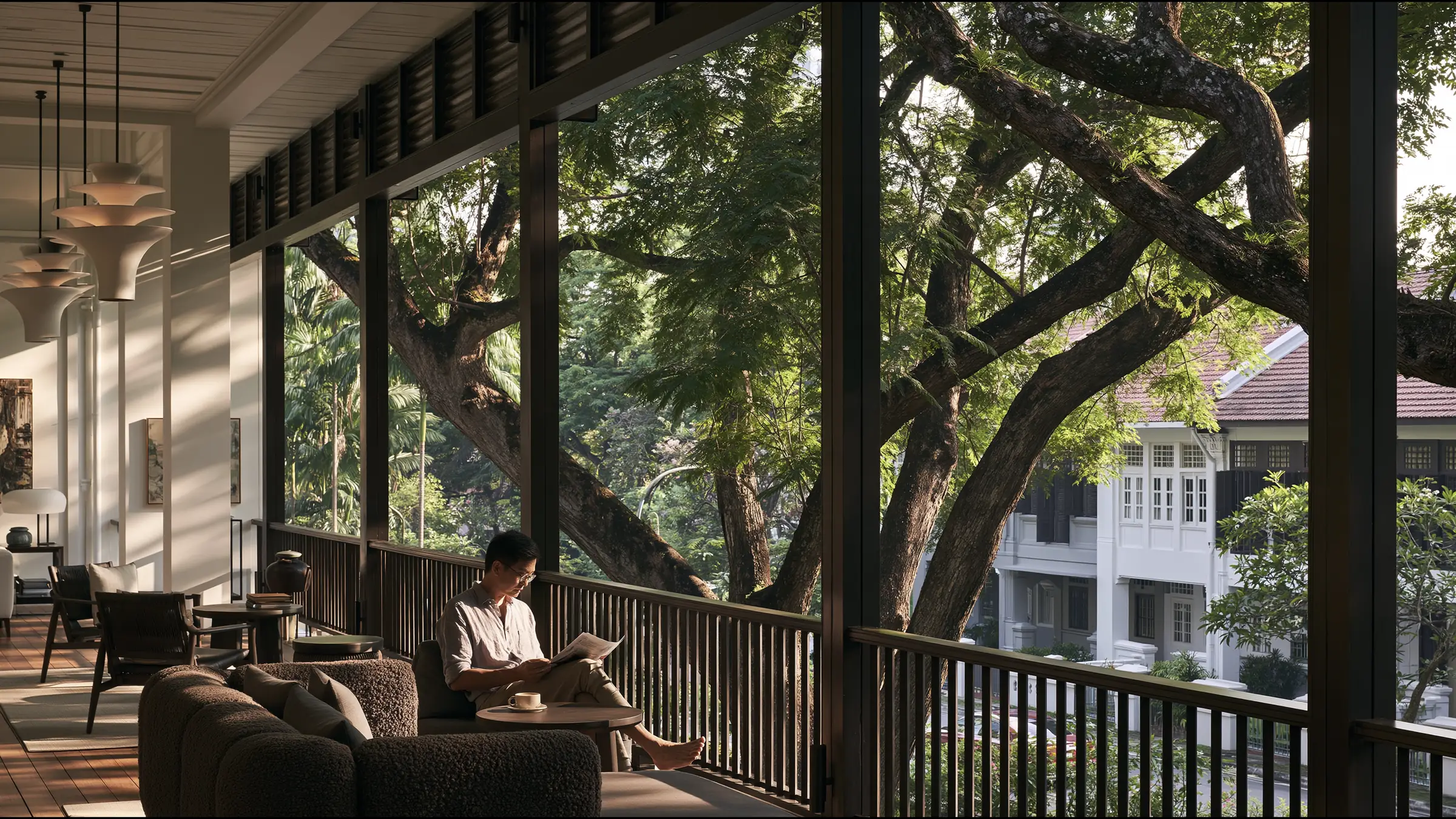 A man in his forties on a vast shaded terrace in Tiong Bahru, Singapore, reading a single printed report with a cup of coffee, unhurried and reassured